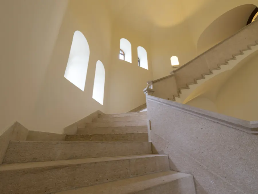 Escalera interior de piedra clara con ventanas